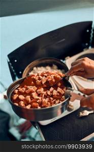 Close up of female hands putting dish with tomato sauce. Woman cooking meal on electric stove on c&ing during summer vacations. C&ing life, preparing a meal. Close up of female hands putting dish with tomato sauce. Woman cooking meal on electric stove on c&ing during summer vacations