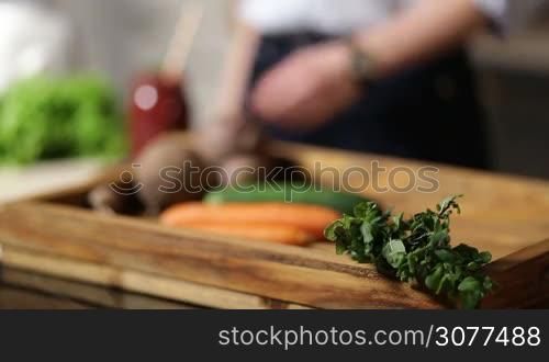 Close up of female hands putting healthy beet smoothie in mason jar with striped straw and leaf of mint for decoration on rustic wooden tray with vegetables. Focus on vegetable smoothie in glass jar. Healthy vegetarian diet for weight loss and detox