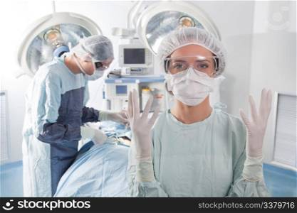 Close-up of female surgeon asking for gloves in middle of operation