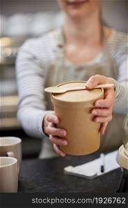 Close Up Of Female Worker in Cafe Serving Meal In Sustainable Recyclable Packaging With Wooden Spoon
