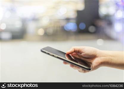 Close-up of female working using smartphone blurred images in Abstract inside shopping mall background.