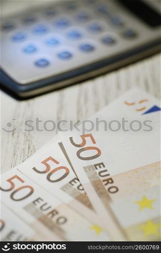 Close-up of fifty Euro banknotes and a calculator