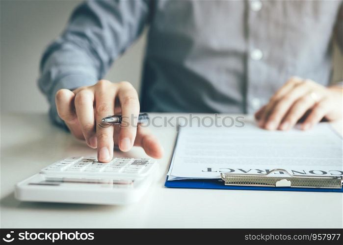 Close up of finger businessman using calculator calculate budget about house contract mortgage in the office room.