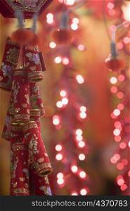 Close-up of firecrackers with decorative electric lights in the background