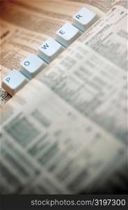 Close-up of five computer keys on a financial newspaper