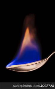 Close up of flaming spoon over black background
