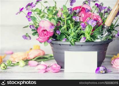 Close up of Flowers pot with shovel and white paper greeting card on table, front view, container gardening concept