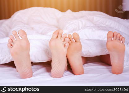 close up of four feet in a bed