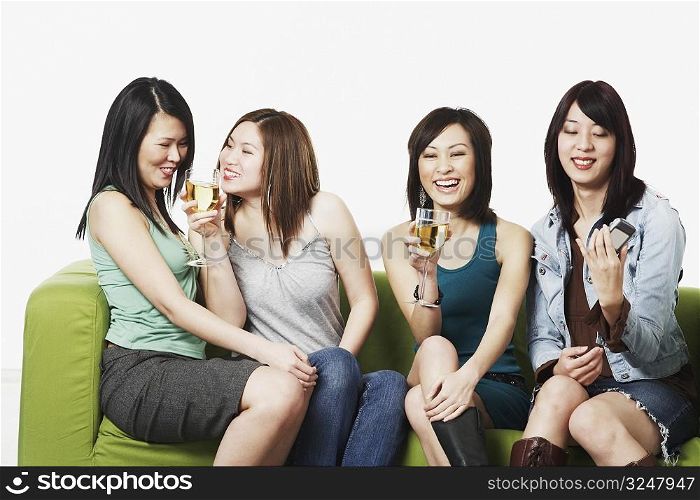 Close-up of four young women sitting on a couch smiling