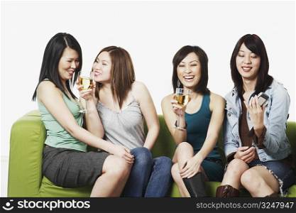 Close-up of four young women sitting on a couch smiling