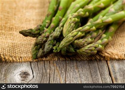 Close up of fresh asparagus on napkin and rustic wood. Selective focus on tips of asparagus.