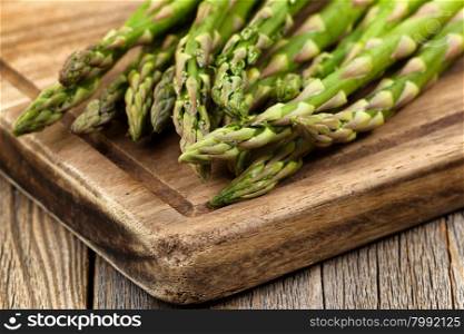 Close up of fresh asparagus on wooden server board. Selective focus on tips of asparagus.