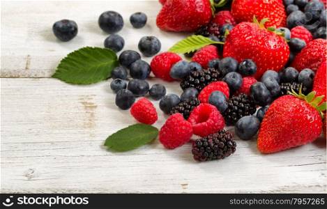 Close up of fresh berries on rustic white wooden table.