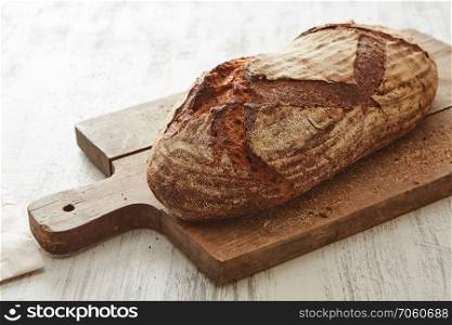 Close-up of fresh bread on a wooden board on a light background. Fresh bread on wooden board