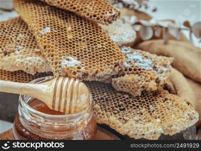 Close- up of Fresh honeycombs with Wooden honey dipper stick on honey glass jar. Healthy organic natura honey, Space for text, Selective focus.