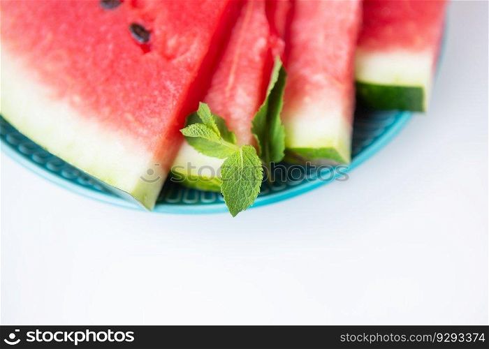 Close-up of fresh slices of watermelon along with mint leaves lie on a plate. Summer food. Close-up of fresh slices of watermelon along with mint leaves lie on a plate. Summer food.