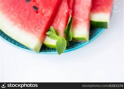 Close-up of fresh slices of watermelon along with mint leaves lie on a plate. Summer food. Close-up of fresh slices of watermelon along with mint leaves lie on a plate. Summer food.