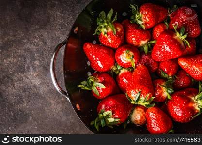 Close up of fresh strawberries in black colander bowl, top view