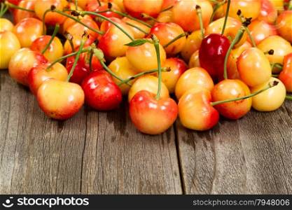 Close up of freshly picked rainier cherries, water droplets on them, on rustic wood.