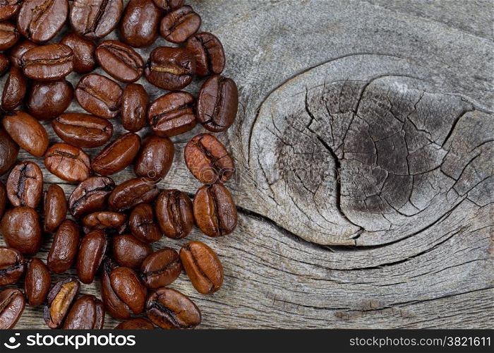 Close up of freshly roasted coffee whole beans on rustic naturally aged wood