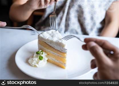 Close up of friends hands enjoy eating cake at restaurant