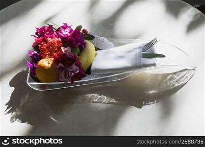 Close-up of fruits and flowers in a glass tray