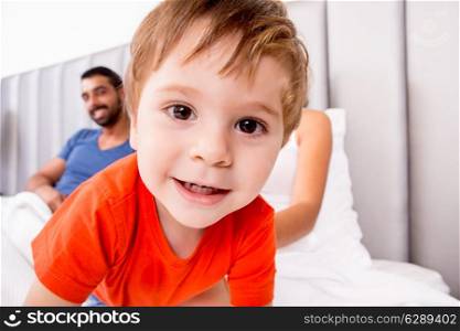 Close up of funny boy playing in bed with family