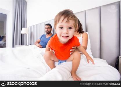 Close up of funny boy playing in bed with family