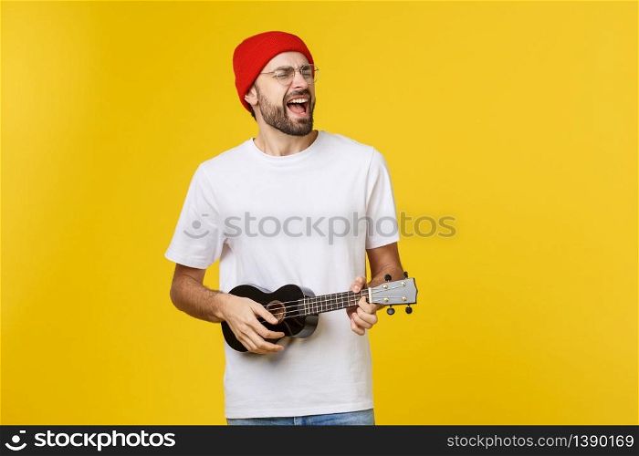 close-up of funny young man playing a guitar. isolated on yellow gold background.. close-up of funny young man playing a guitar. isolated on yellow gold background