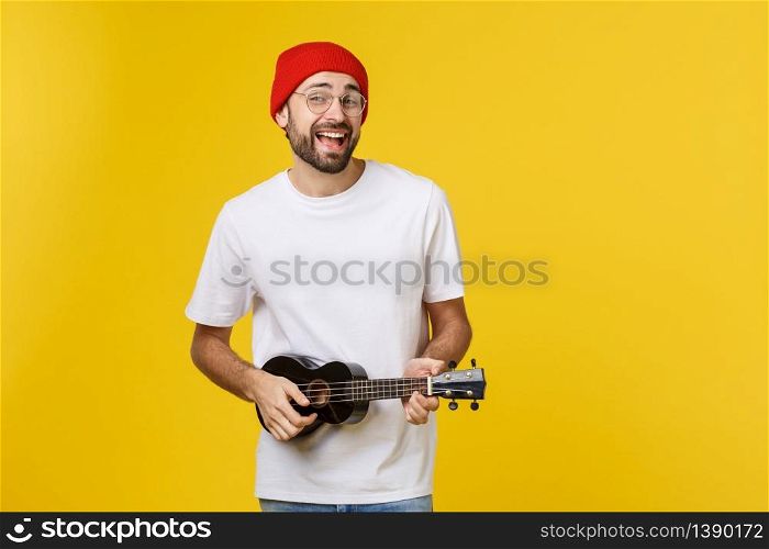 close-up of funny young man playing a guitar. isolated on yellow gold background.. close-up of funny young man playing a guitar. isolated on yellow gold background