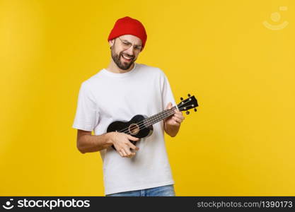 close-up of funny young man playing a guitar. isolated on yellow gold background.. close-up of funny young man playing a guitar. isolated on yellow gold background