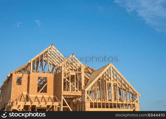 Close-up of gables roof on stick built home under construction and blue sky in Humble, Texas, USA. New build roof with wooden truss, post and beam framework. Timber frame house, real estate background