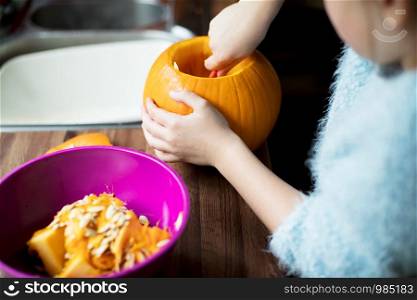 Close Up of Girl Hollowing Out Pumpkin To Make Halloween Lantern