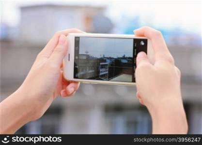 Close up of girl?s hands taking picture with smartphone on city