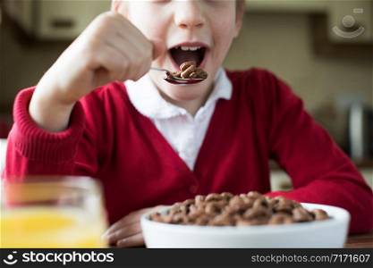 Close Up Of Girl Wearing School Uniform Eating Bowl Of Sugary Breakfast Cereal In Kitchen