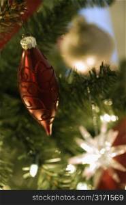 Close up of gold and red ornaments hanging in Christmas tree.