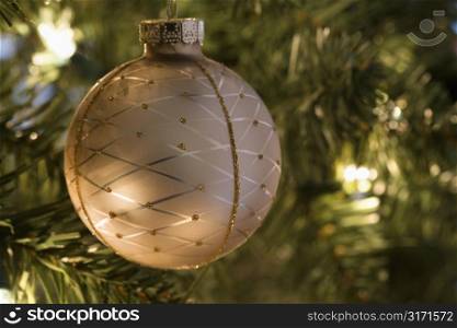 Close up of gold ornament hanging in Christmas tree.