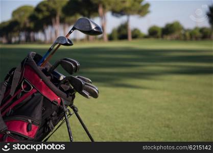 close up of golf bag on course with club and ball in front at beautiful sunrise