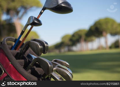 close up of golf bag on course with club and ball in front at beautiful sunrise