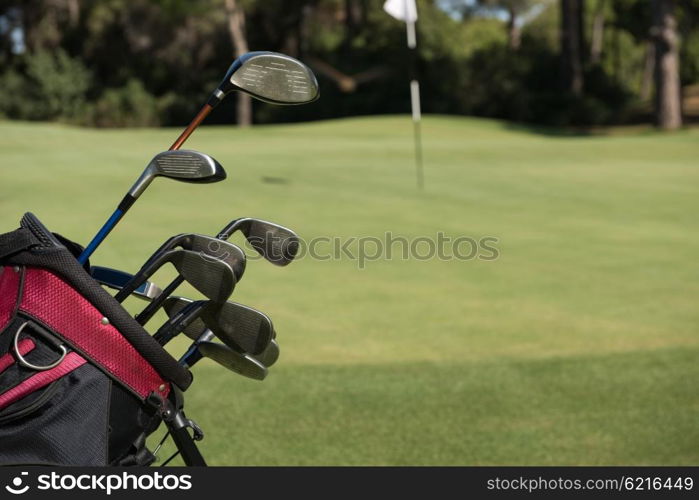 close up of golf bag on course with club and ball in front at beautiful sunrise