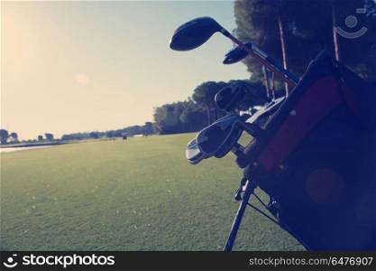 close up of golf bag on course with club and ball in front at beautiful sunrise. close up golf bag on course