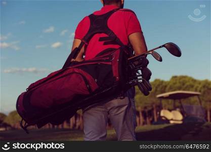 close up of golfers back while carrying golf bag and walking at course to next hole. close up of golfers back while walking and carrying golf bag