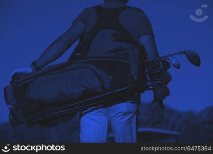 close up of golfers back while walking and carrying golf bag. close up of golfers back while carrying golf bag and walking at course to next hole duo tone