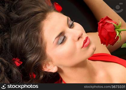 close up of graceful woman with red lips kissing a rose