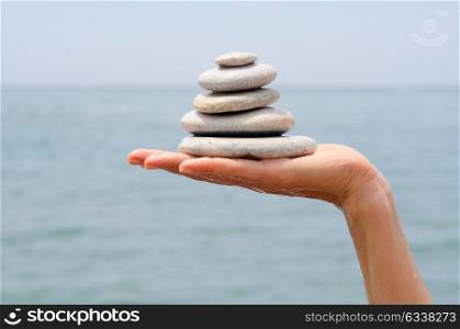 Close-up of gravel pile in woman&rsquo;s hands with sea background