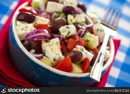 Close up of greek salad with feta cheese tomatoes cucumber olives and onions over a red napkin. Close up of greek salad with feta cheese tomatoes cucumber olives and onions