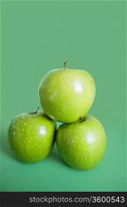Close-up of green apples in pyramid stack over colored background