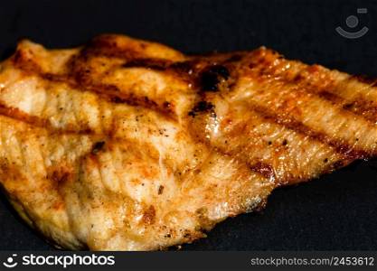 Close up of grilled steak on small black chopping board isolated. Barbecue, grill and food concept.