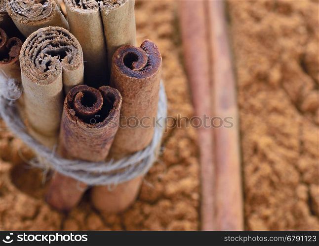 Close-up of ground cinnamon with stack of sticks tied with rope