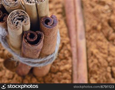 Close-up of ground cinnamon with stack of sticks tied with rope